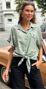 Uma bluse med bindebånd og broderet blomst foran khaki LikeLondon